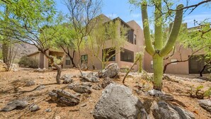 Un bâtiment de style désertique, doté d’une architecture moderne, entouré de cactus et de rochers.