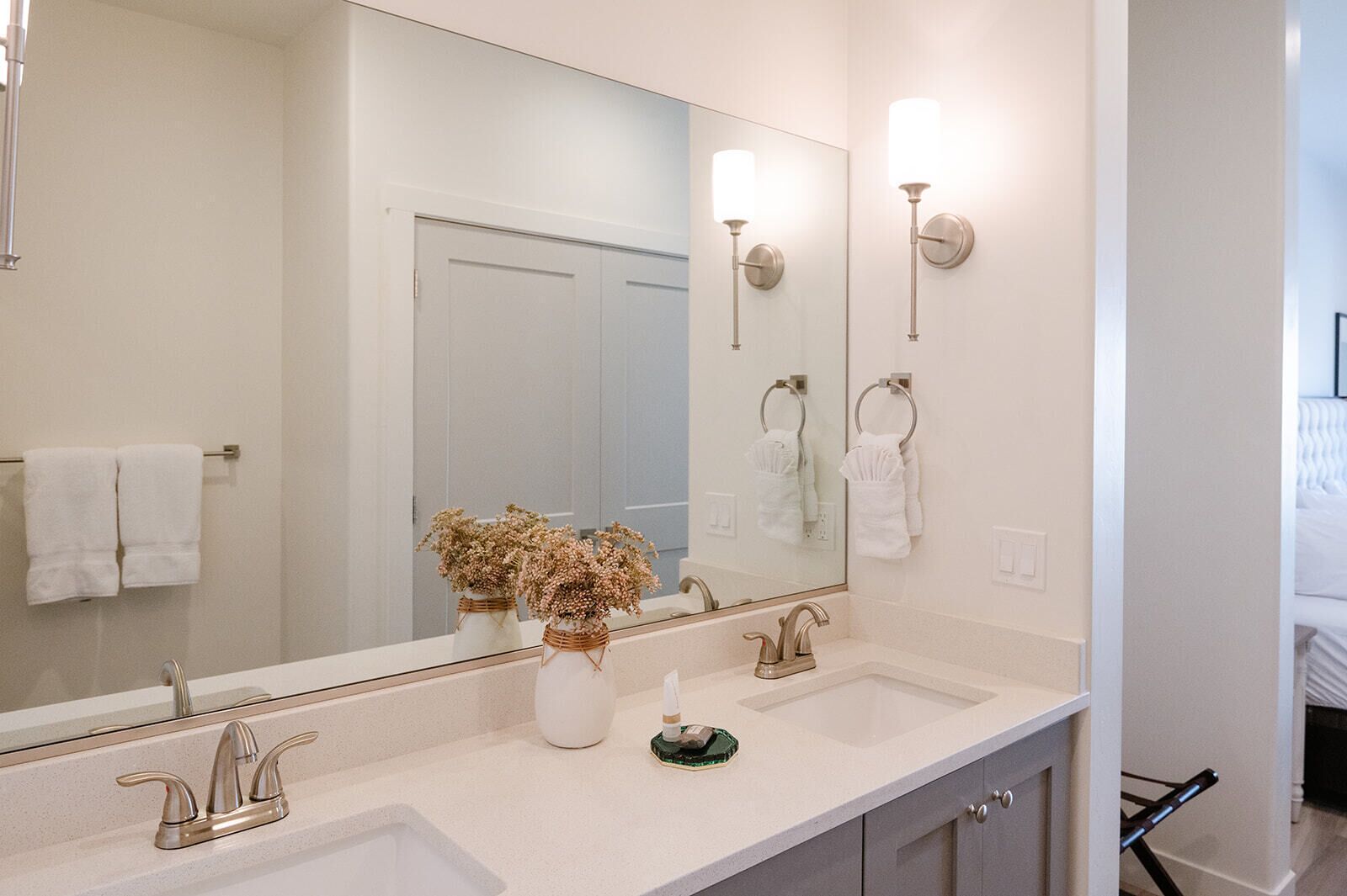 Une salle de bain avec un grand miroir, deux lavabos et un porte-serviettes.