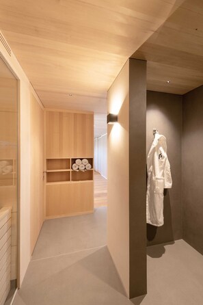 A modern bathroom with a wooden vanity, a towel rack, and a shower area.