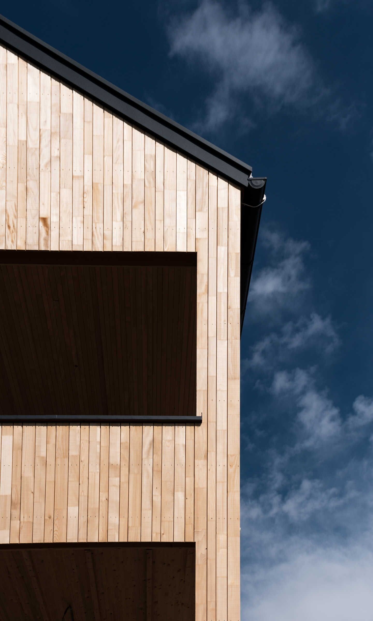 Un edificio con fachada de madera y techo negro.