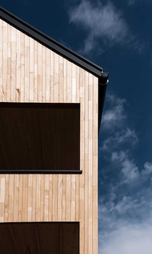 A building with a wooden exterior and a black roof. - Apartment 2 - Apartments Poldi (Sulzberg)