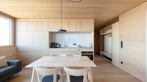 Een moderne keuken met houten plafond, een eettafel met stoelen en een bank.