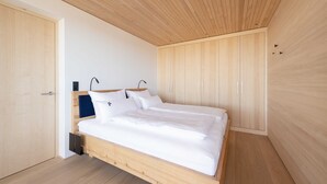 Een moderne slaapkamer met een houten bed, een inbouwkast en een houten plafond.