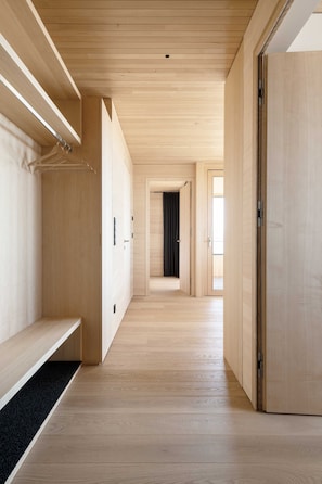 A hallway with wooden flooring and walls, leading to a room with a black curtain. - Apartment 2 - Apartments Poldi (Sulzberg)