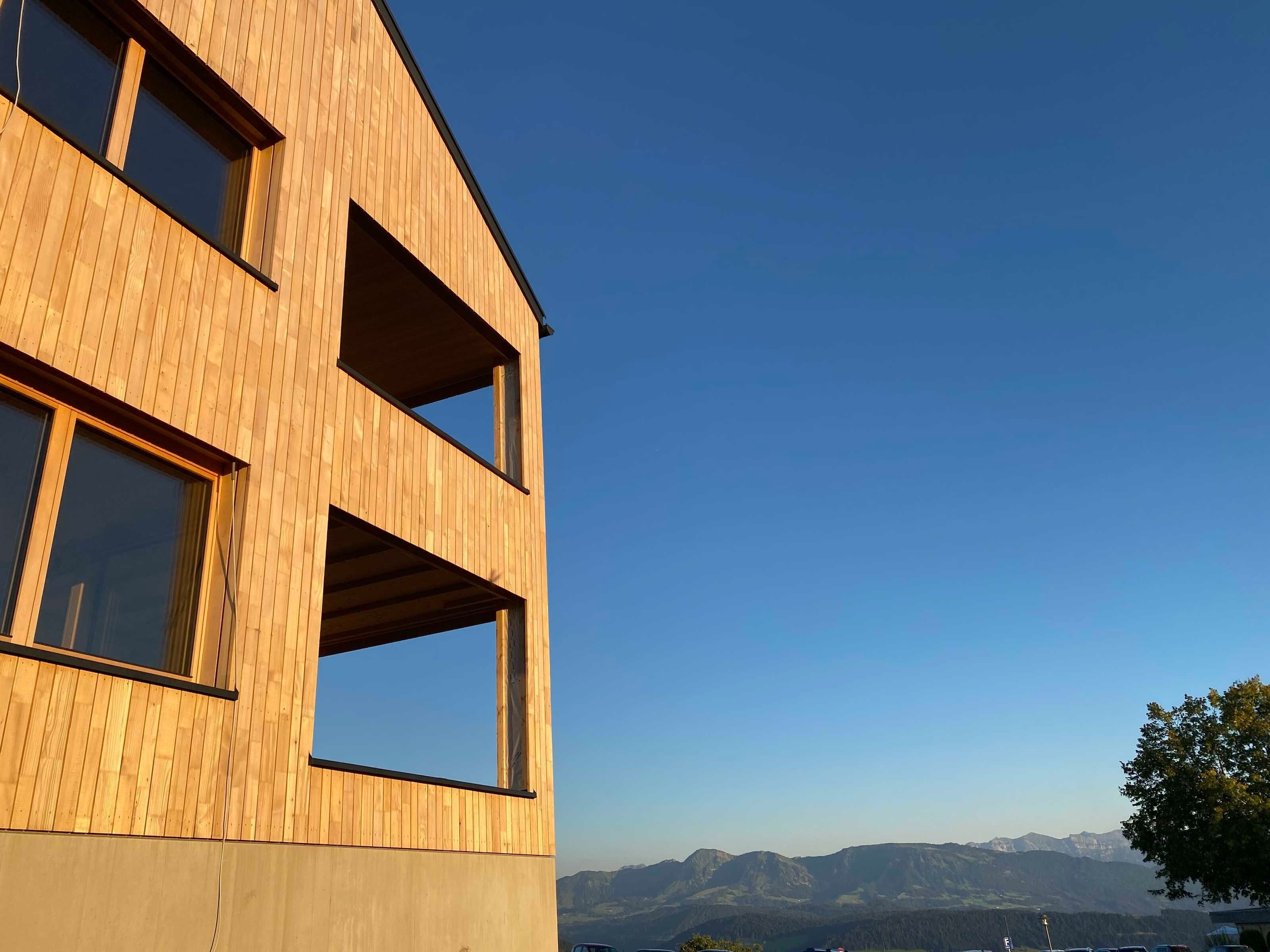 A modern building with a wooden facade and multiple windows.