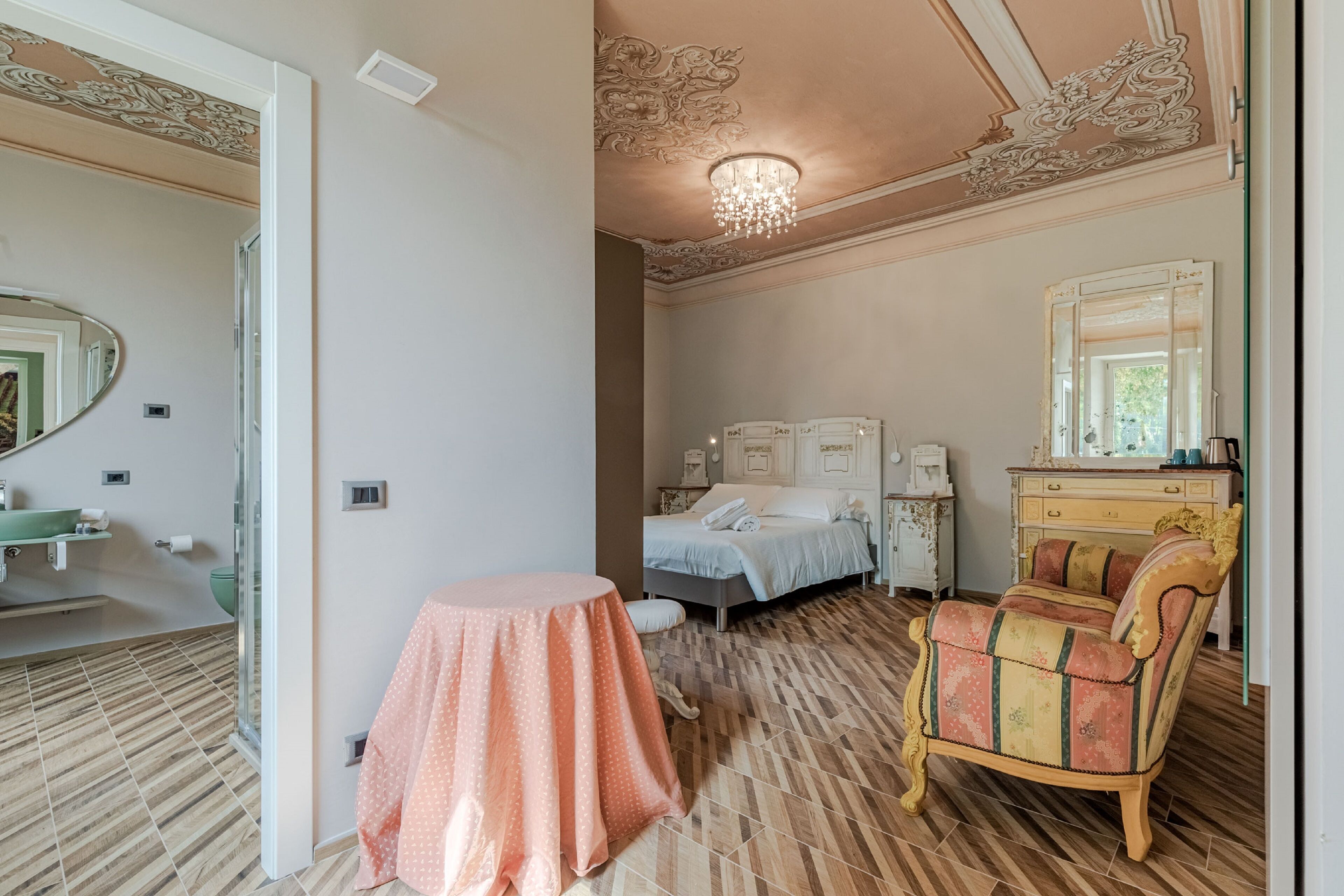 Un dormitorio con una cama, un tocador con espejo, una mesita redonda y una silla.
