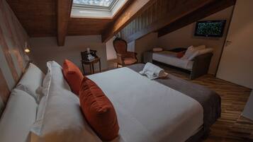 Een slaapkamer met een groot bed, houten plafond, dakraam, televisie aan de muur en een bank.
