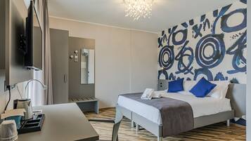 Ein modernes Hotelzimmer mit Bett, Schreibtisch und einer großen abstrakten Wandmalerei.