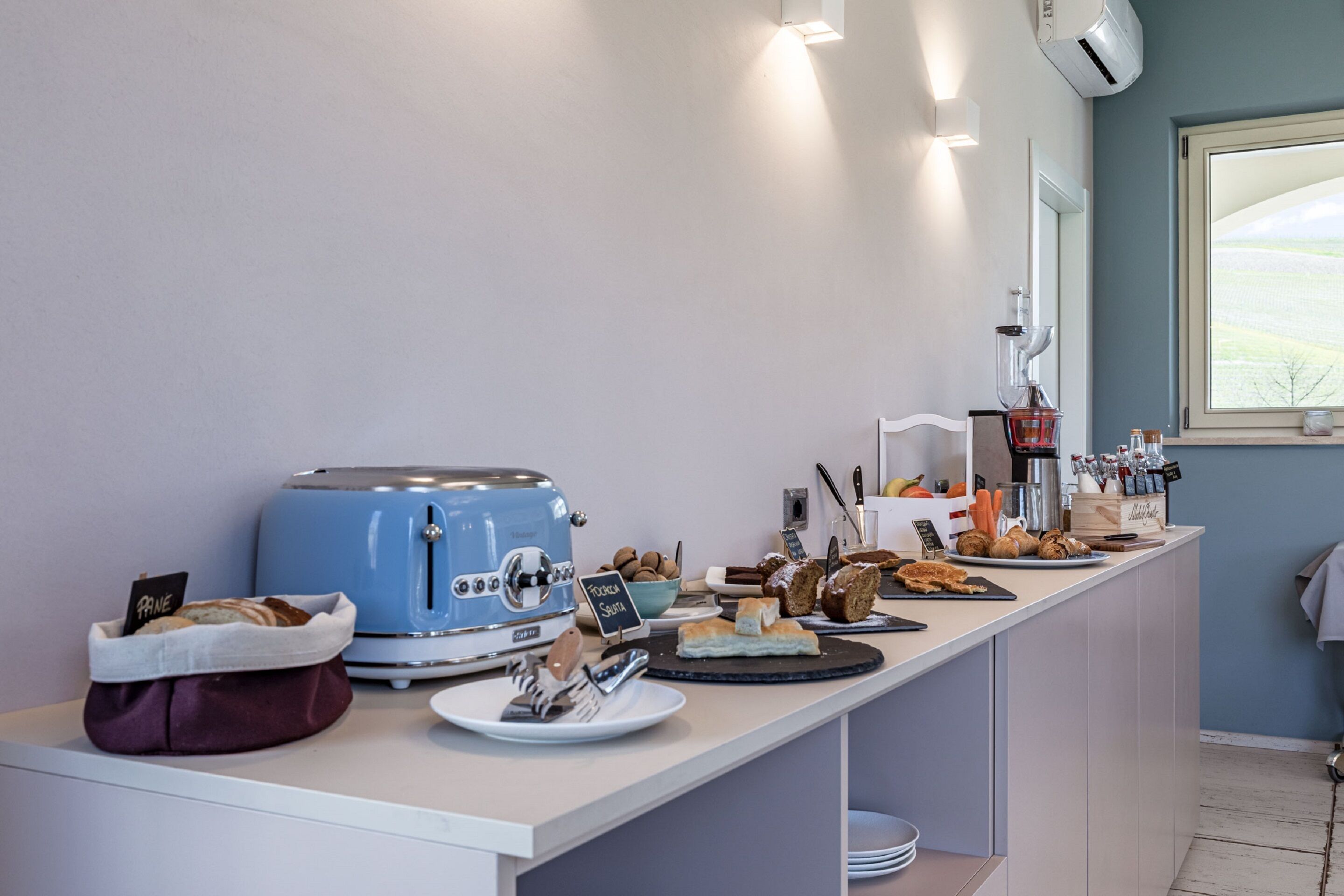 Un bar pour le petit-déjeuner avec un grille-pain bleu, une variété de viennoiseries et un coin café.