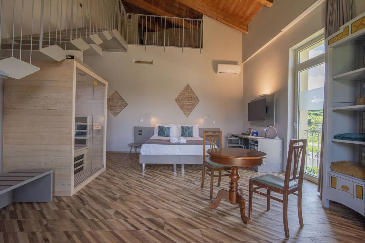 Un dormitorio moderno con cama, mesita de noche y televisor. Tiene un balcón con vistas.
