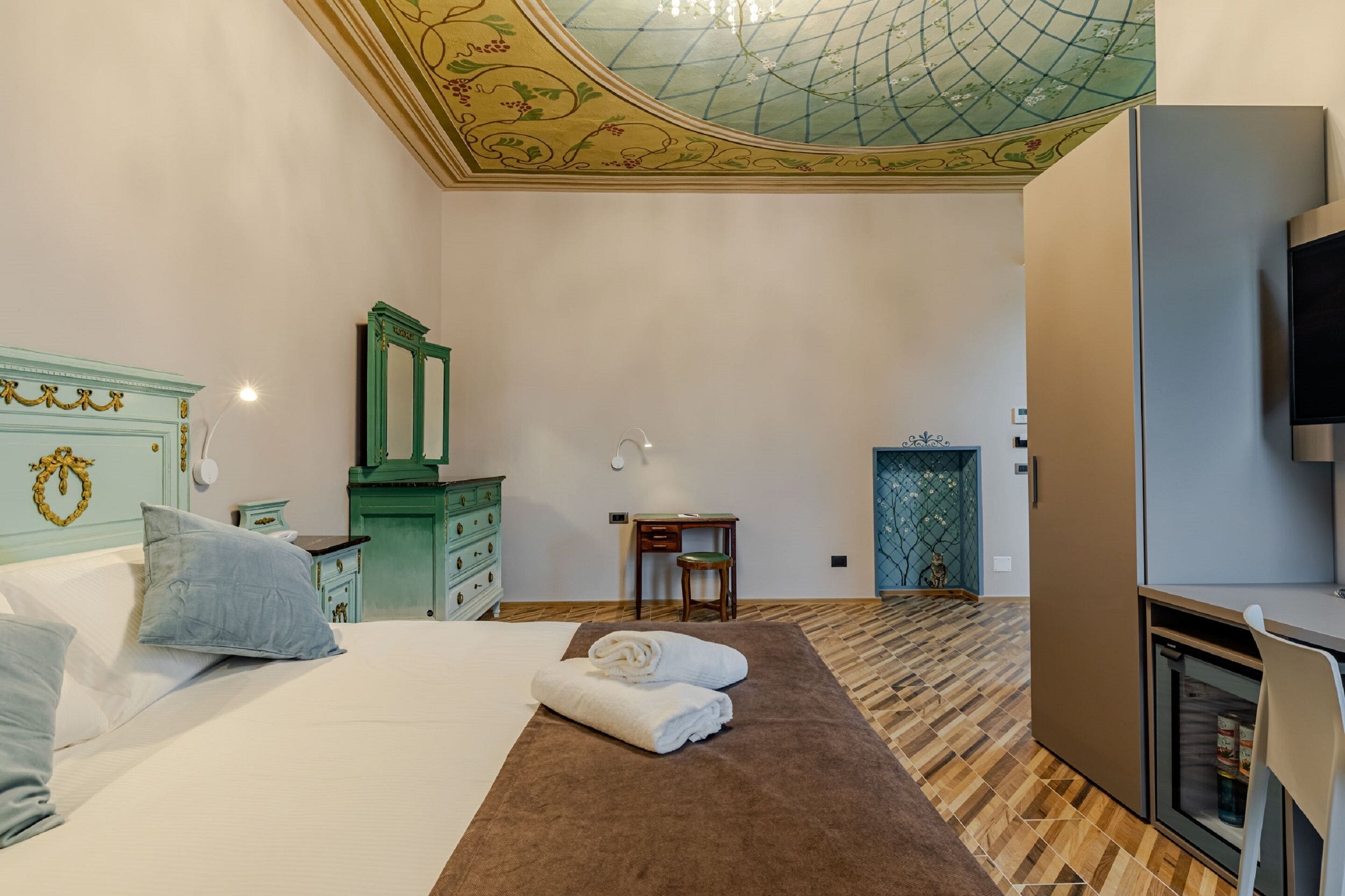 Ein Hotelzimmer mit Bett, Schreibtisch, Spiegel, Kleiderschrank und Fernseher.