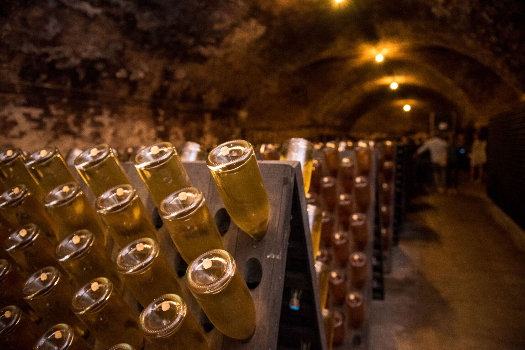 A wine cellar with rows of wine bottles and a wooden rack holding more bottles.