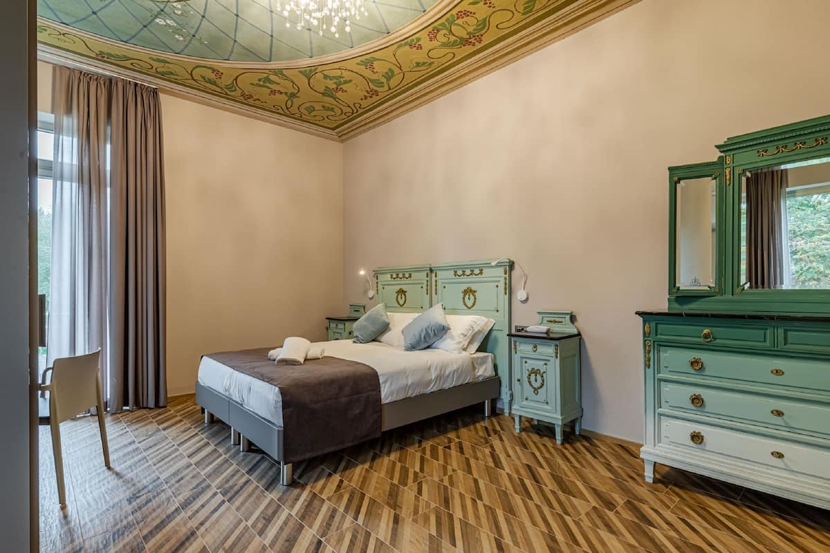 Un dormitorio con cama, mesitas de noche, cómoda y espejo.