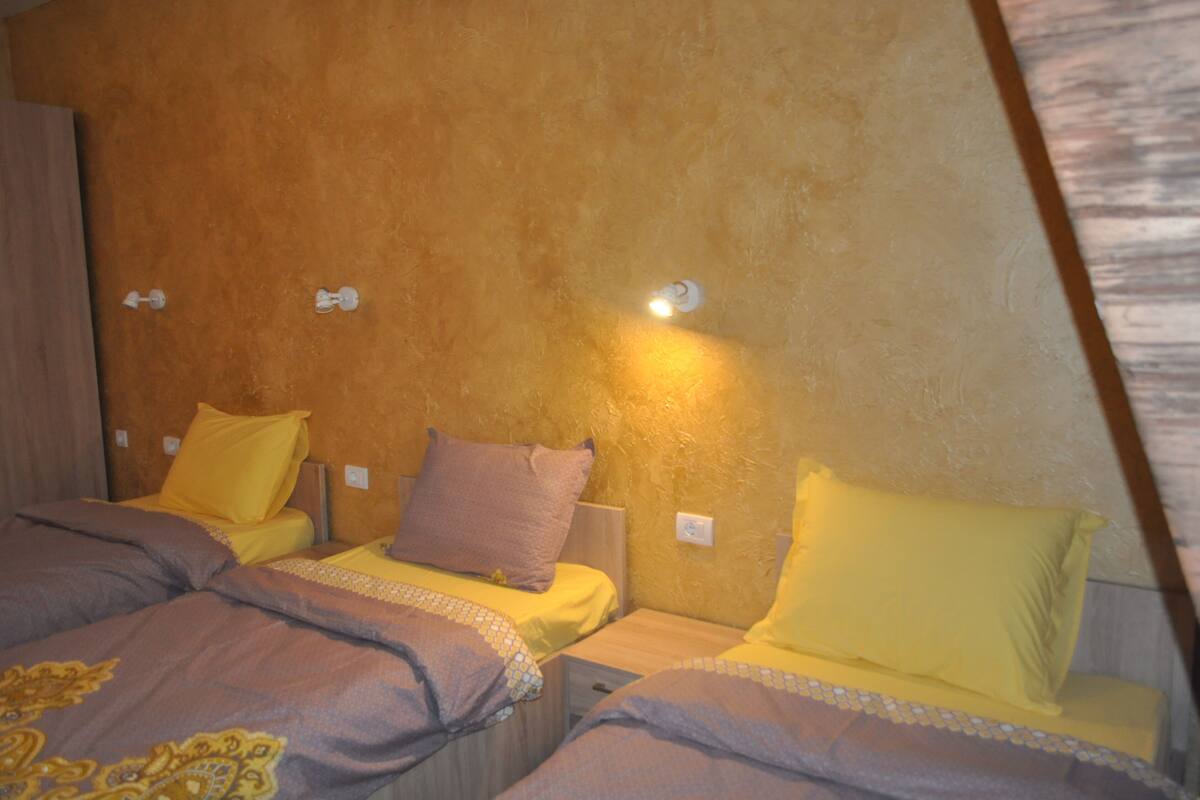 A bedroom with two beds, each with yellow and brown bedding.