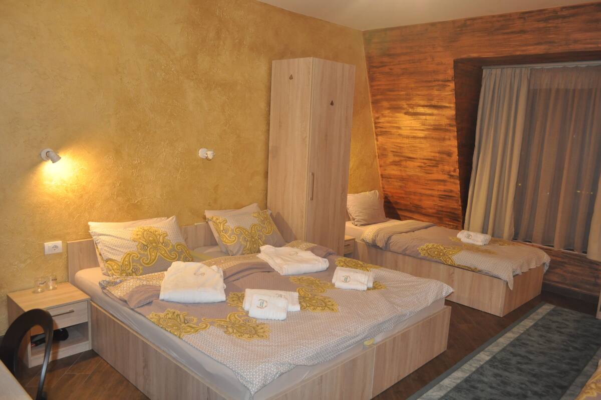 A hotel room with two beds, wooden wardrobe, and a large mirror.