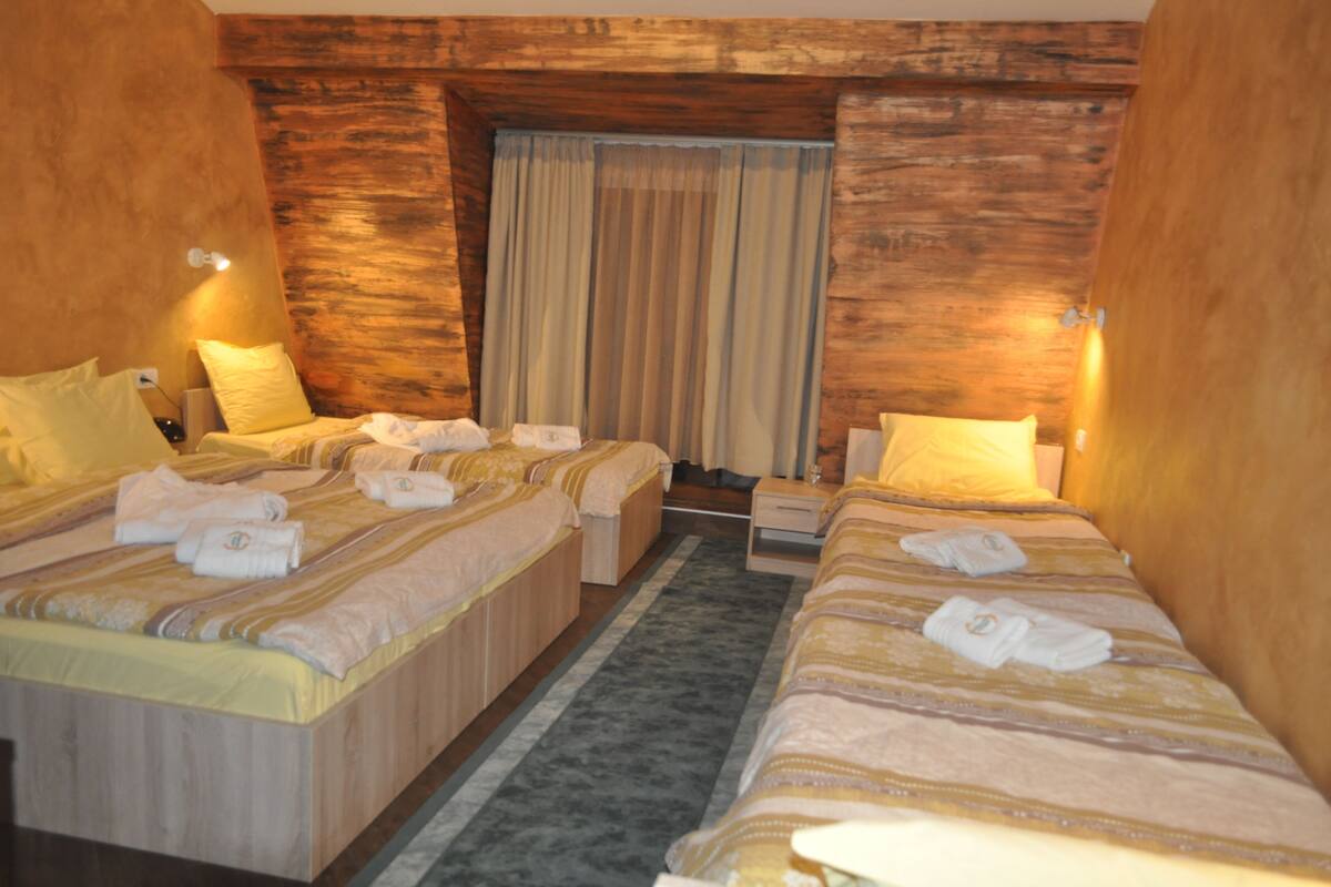 A hotel room with two beds, each with a wooden headboard, a small bedside table, and a lamp.