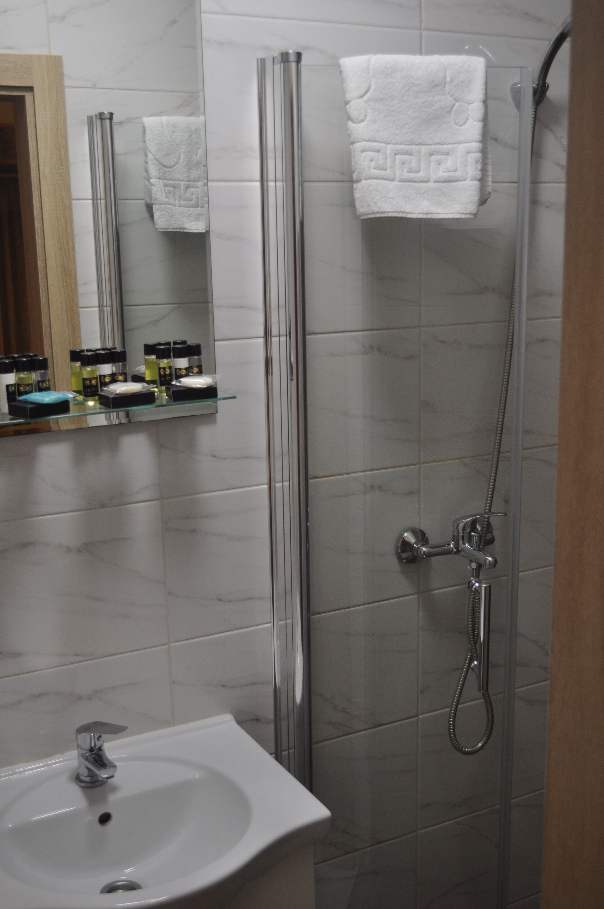 Un baño con cabina de ducha de vidrio, un lavabo blanco y un espejo sobre el lavabo.
