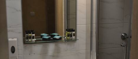 A bathroom with a white sink, a mirror, a glass shower enclosure, and a towel hanging on the wall.