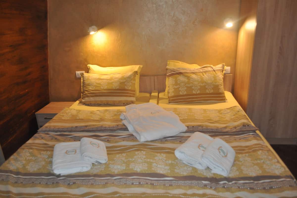 A hotel room with a bed, two pillows, and folded towels on the bed.