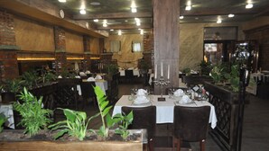 Un restaurant aux murs de briques, aux tables en bois et aux plantes en pot.