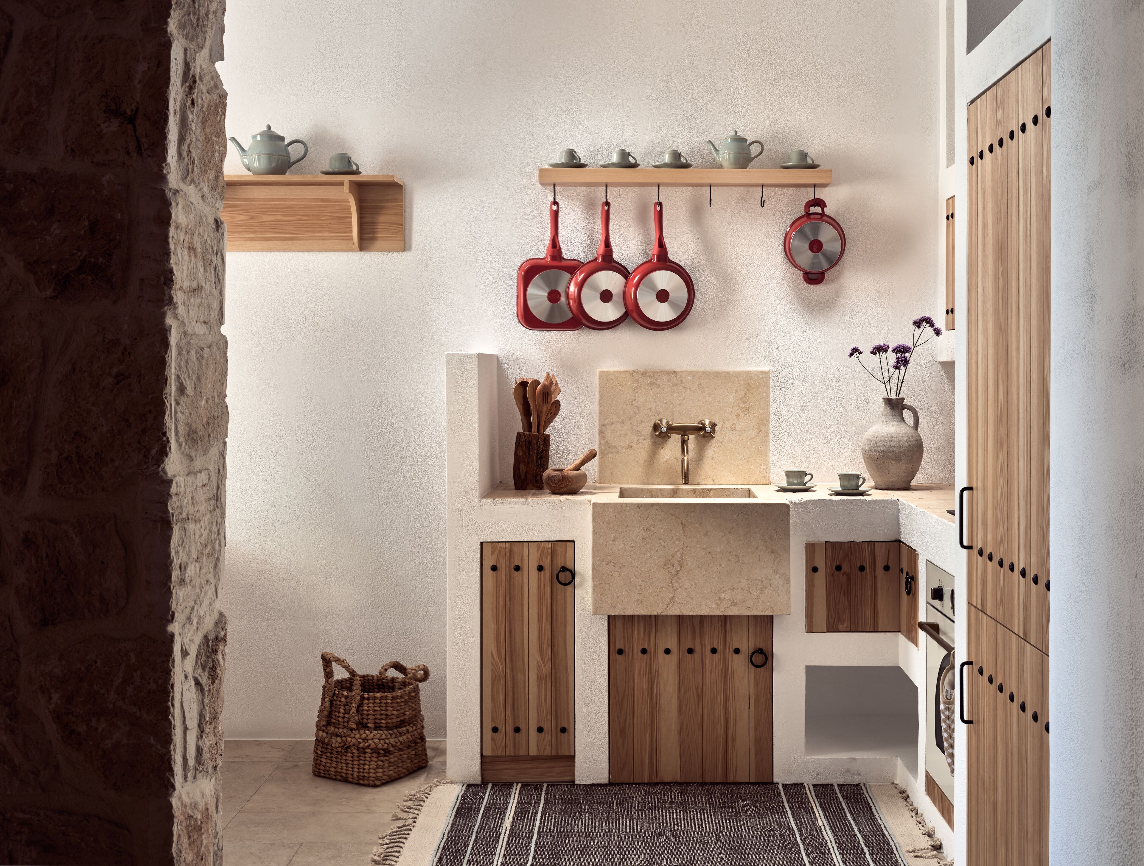 A compact kitchen with wooden cabinets, a sink, and hanging pots.