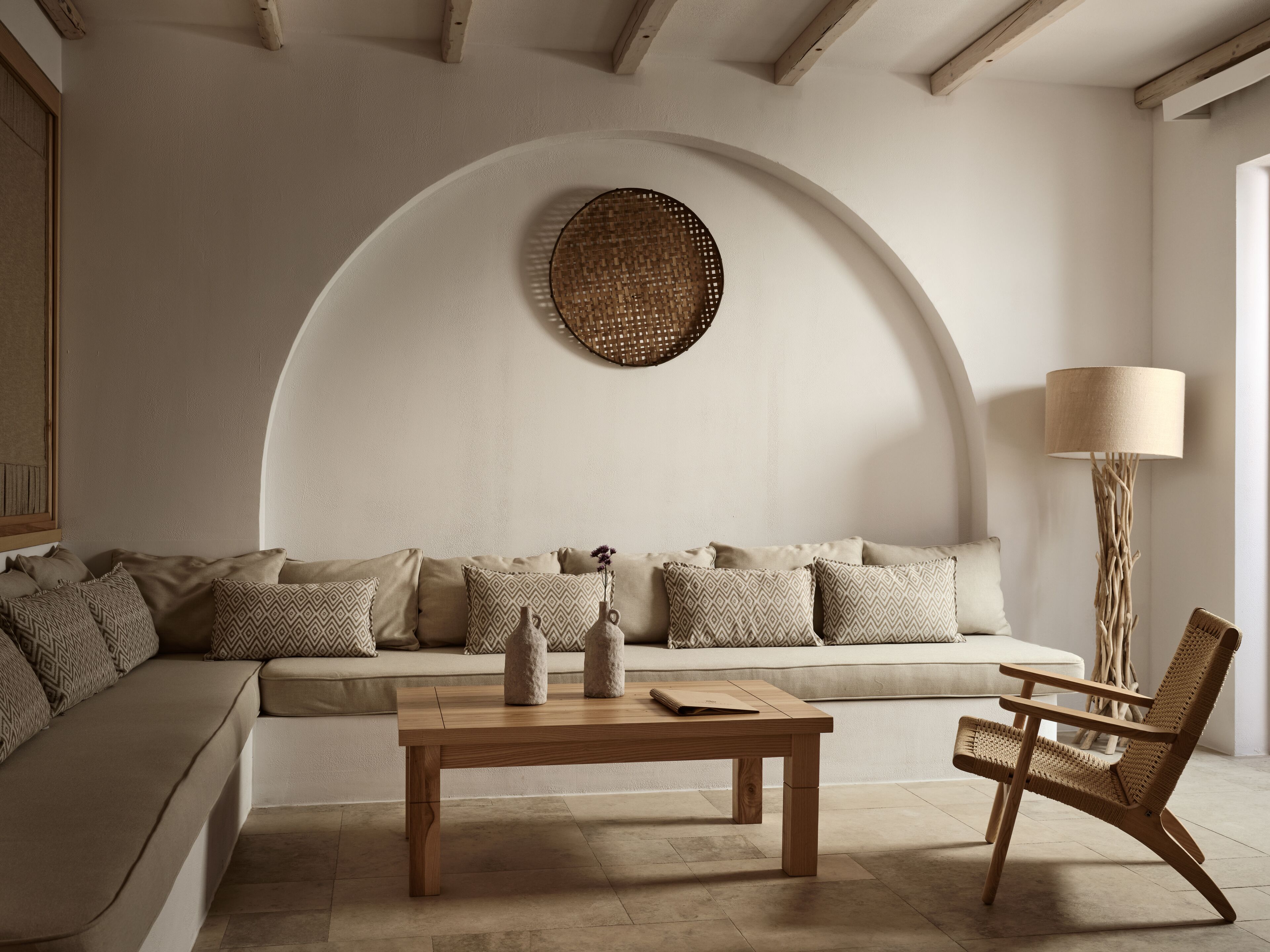 A modern living room with a sofa, a wooden coffee table, and a woven wall hanging.