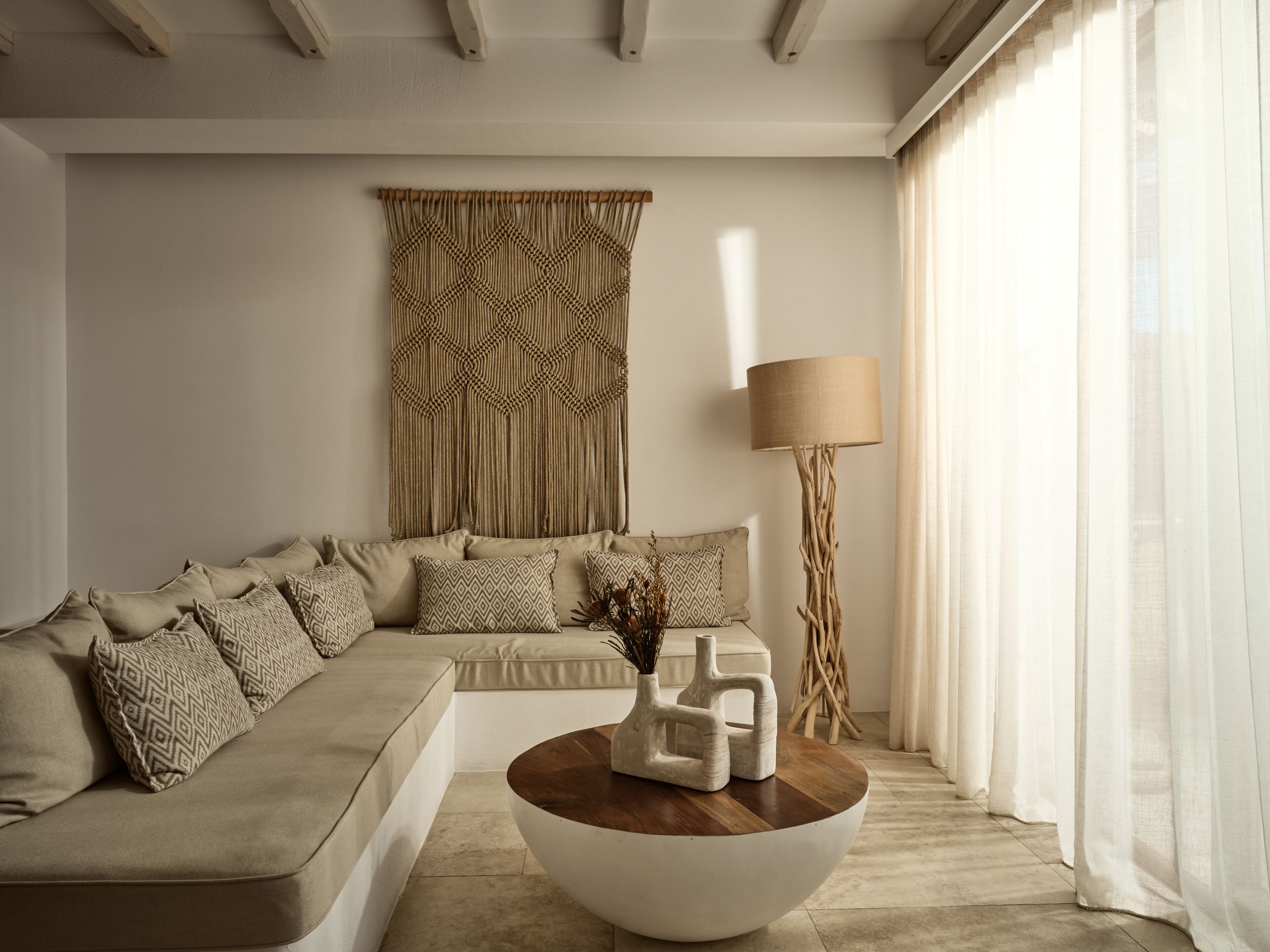 Un soggiorno moderno con un divano color beige, cuscini decorati, un tavolino in legno e una lampada da terra.
