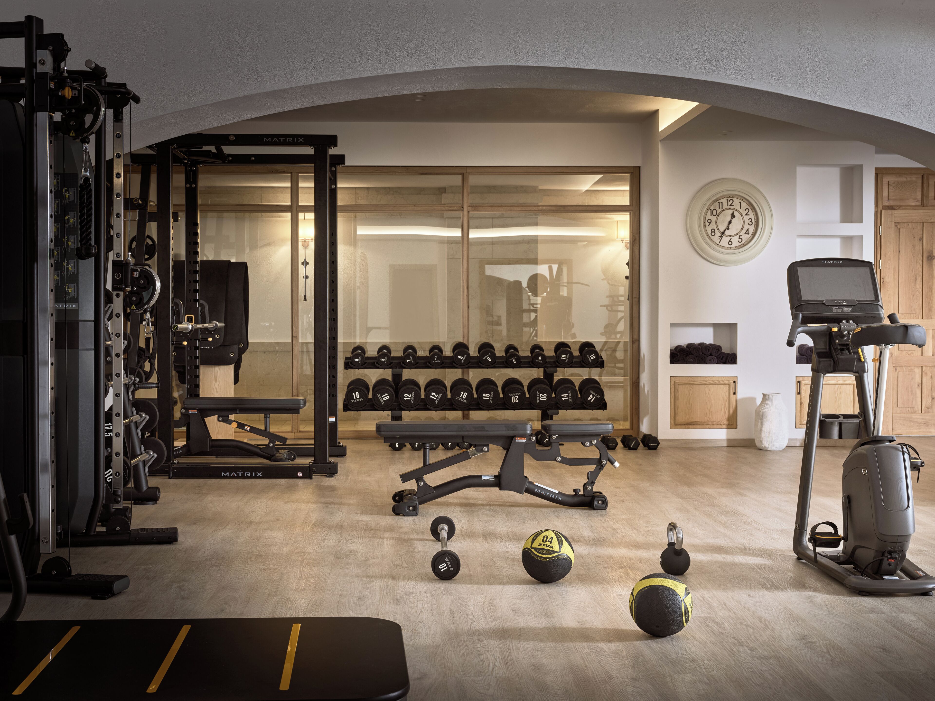 Een sportschool thuis, met diverse apparaten zoals een squat rek, bankdrukapparaat, gewichten en een loopband.