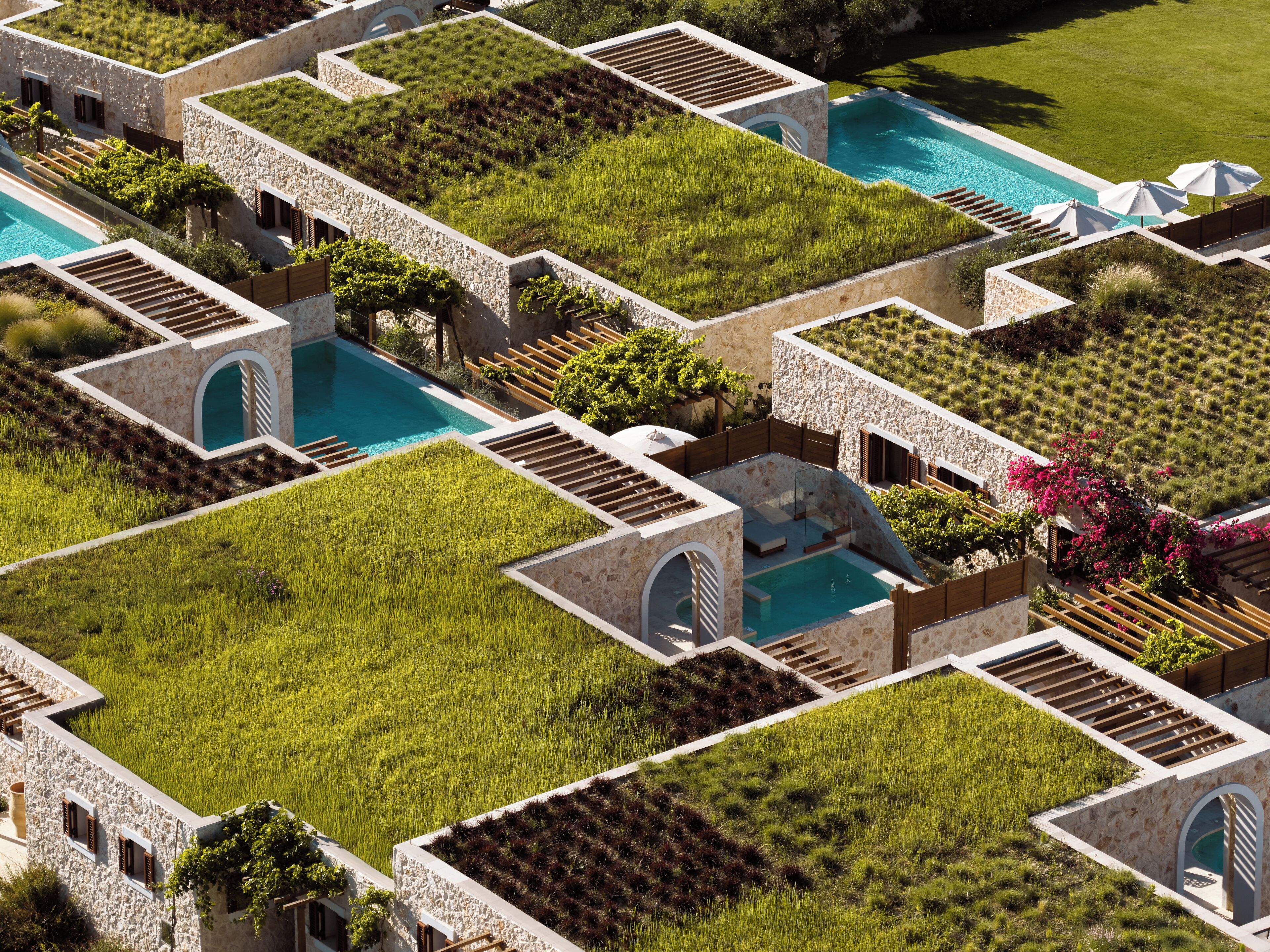 A modern resort with rooftop gardens, swimming pools, and stone architecture.
