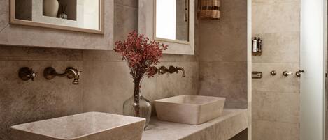 A modern bathroom with two large vessel sinks, a mirror, and a hanging wicker light fixture.