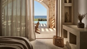 A bedroom with a view of the sea, a stone archway, a statue, and a vase on a shelf. - Lesante Cape - The Leading Hotels of the World (Zakynthos)