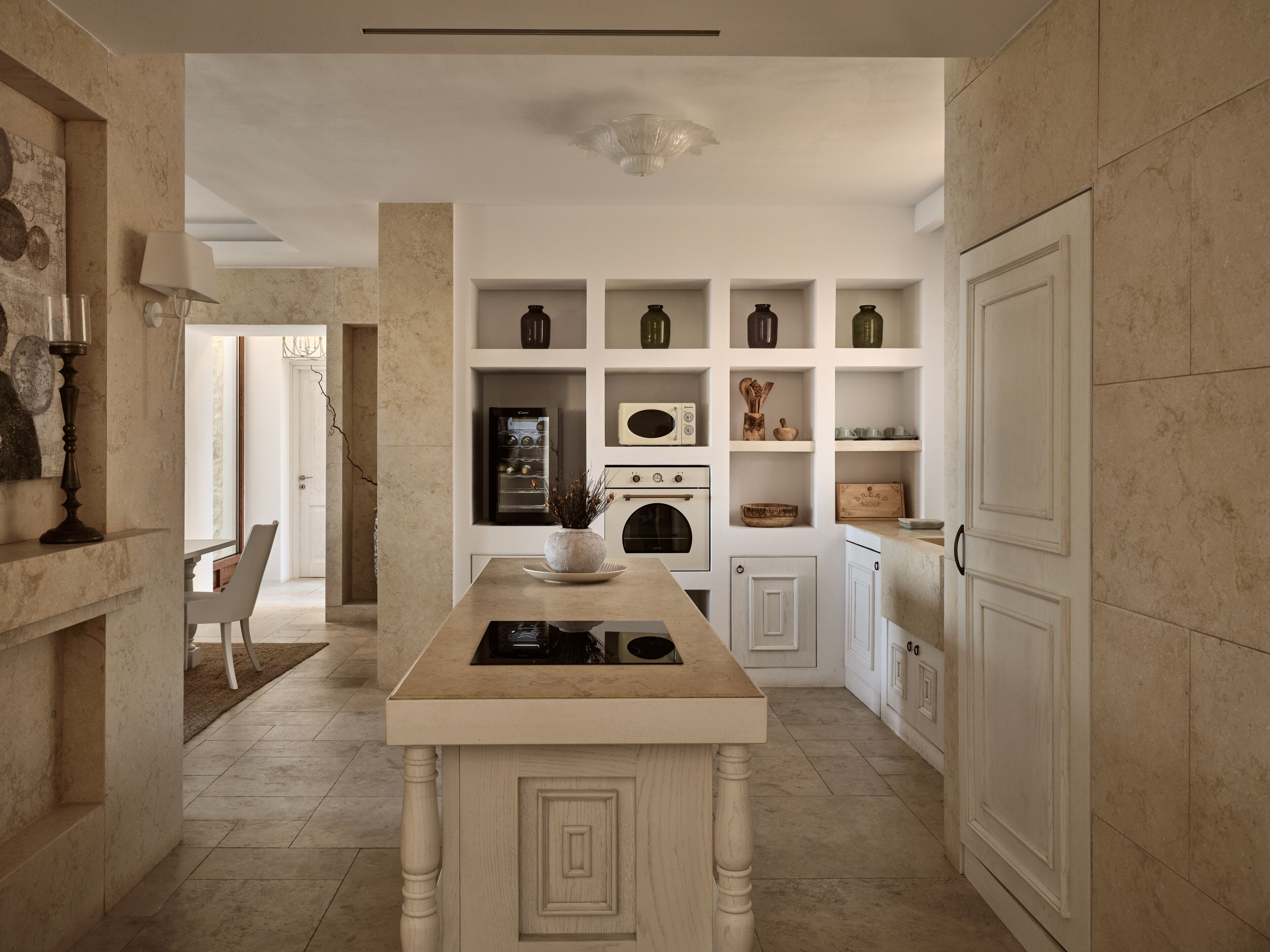 A modern kitchen with white cabinetry, a central island, and a built-in oven.