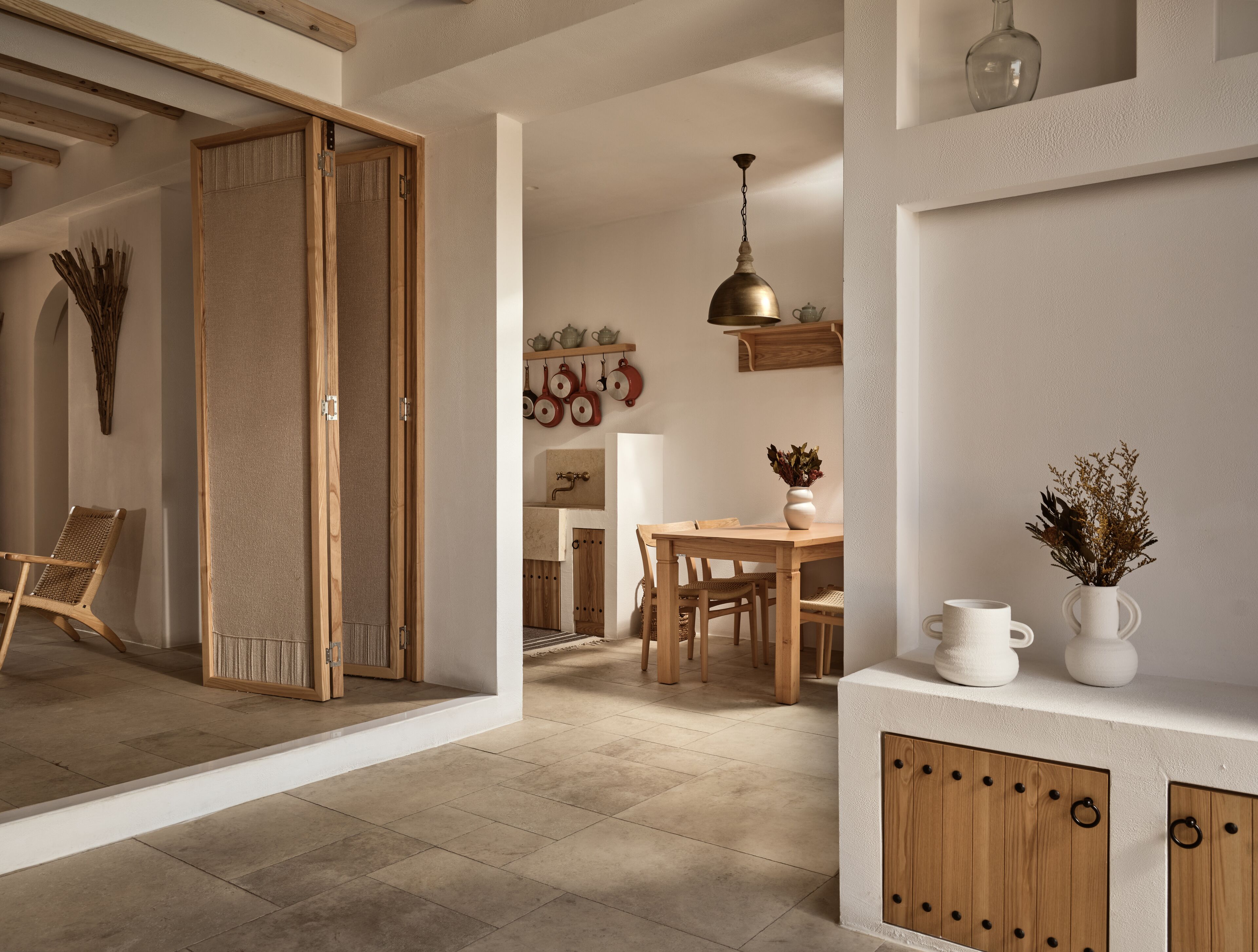 A modern kitchen with wooden cabinets, a dining table, and a hanging pot rack.