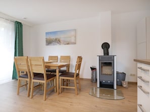 Un coin repas avec une table et des chaises, un poêle à bois et un tableau accroché au mur.