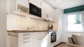 A modern kitchen with white cabinets, a built-in oven, a microwave, and a coffee maker. - Urlauberdorf 50a, Deutschland (Ostseebad Boltenhagen)
