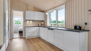 Een moderne keuken met witte kasten, een houten vloer en een raam met uitzicht op groen.