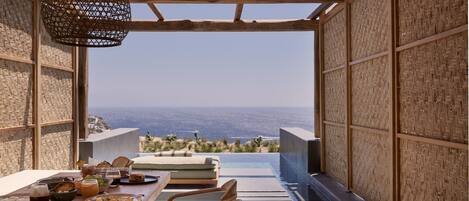A dining area with a table set for breakfast, overlooking a pool and a scenic view.