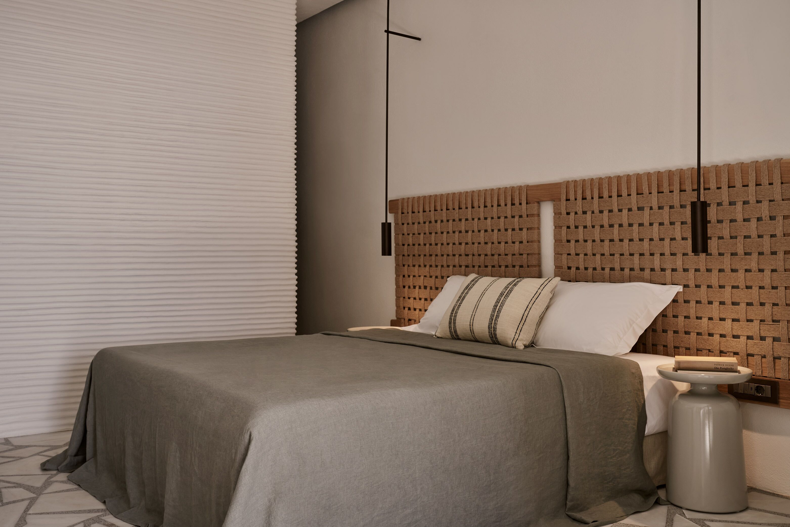 Une chambre moderne avec un lit, une table de chevet et un luminaire fixé au mur.