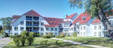 Ein modernes Gebäude mit mehreren Stockwerken, großen Fenstern und einem roten Dach.