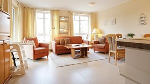 A spacious living room with a sofa set, a coffee table, and a dining area with a table and chairs. - Likedeeler Whg. Li20 (Ostseebad Boltenhagen)
