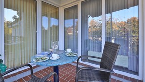 A covered patio with a round table, chairs, and a glass bowl of seashells. - Likedeeler Whg. Li20 (Ostseebad Boltenhagen)