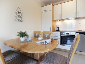 A compact kitchen with white cabinets, a built-in oven, and a coffee maker.