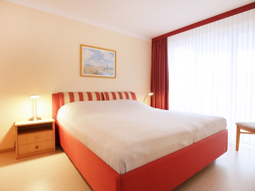 Een hotelkamer met een groot bed, een nachtkastje, een stoel en een schilderij aan de muur.