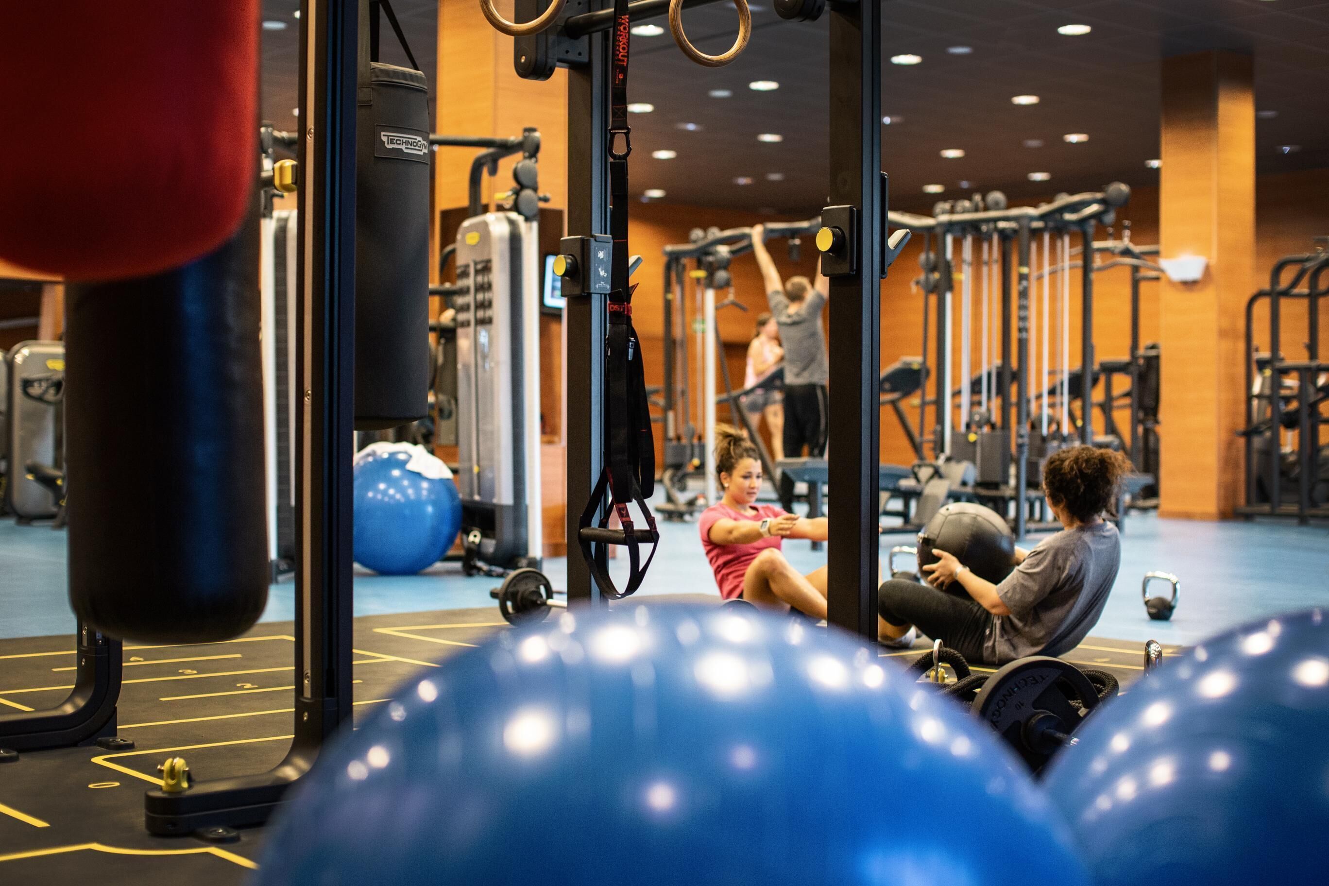 A gym with exercise equipment, including a punching bag, a pull-up bar, and a squat rack.