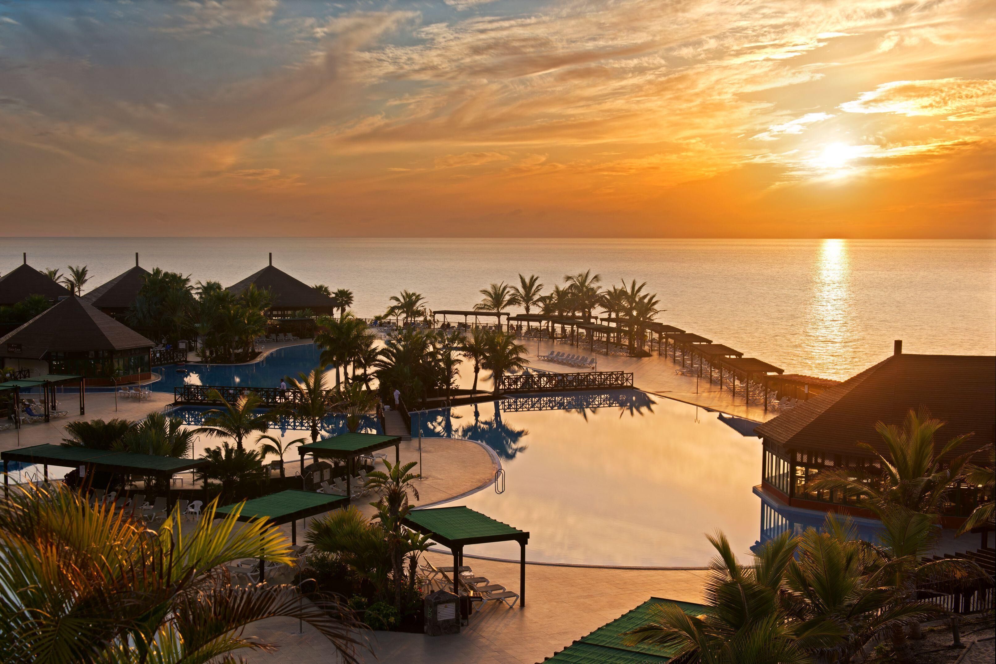 A resort with a pool, palm trees, and a sunset view.
