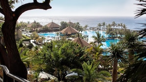 A resort with a large pool, palm trees, and a view of the ocean.