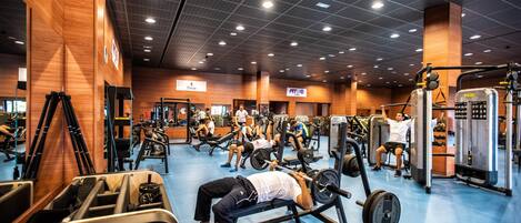 Ein Fitnessstudio mit verschiedenen Trainingsgeräten, darunter Kraftgeräte und Kurzhanteln.