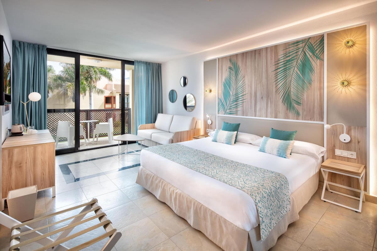 Une chambre d’hôtel moderne dotée d’un grand lit, d’un balcon avec vue, d’un bureau et d’une chaise.