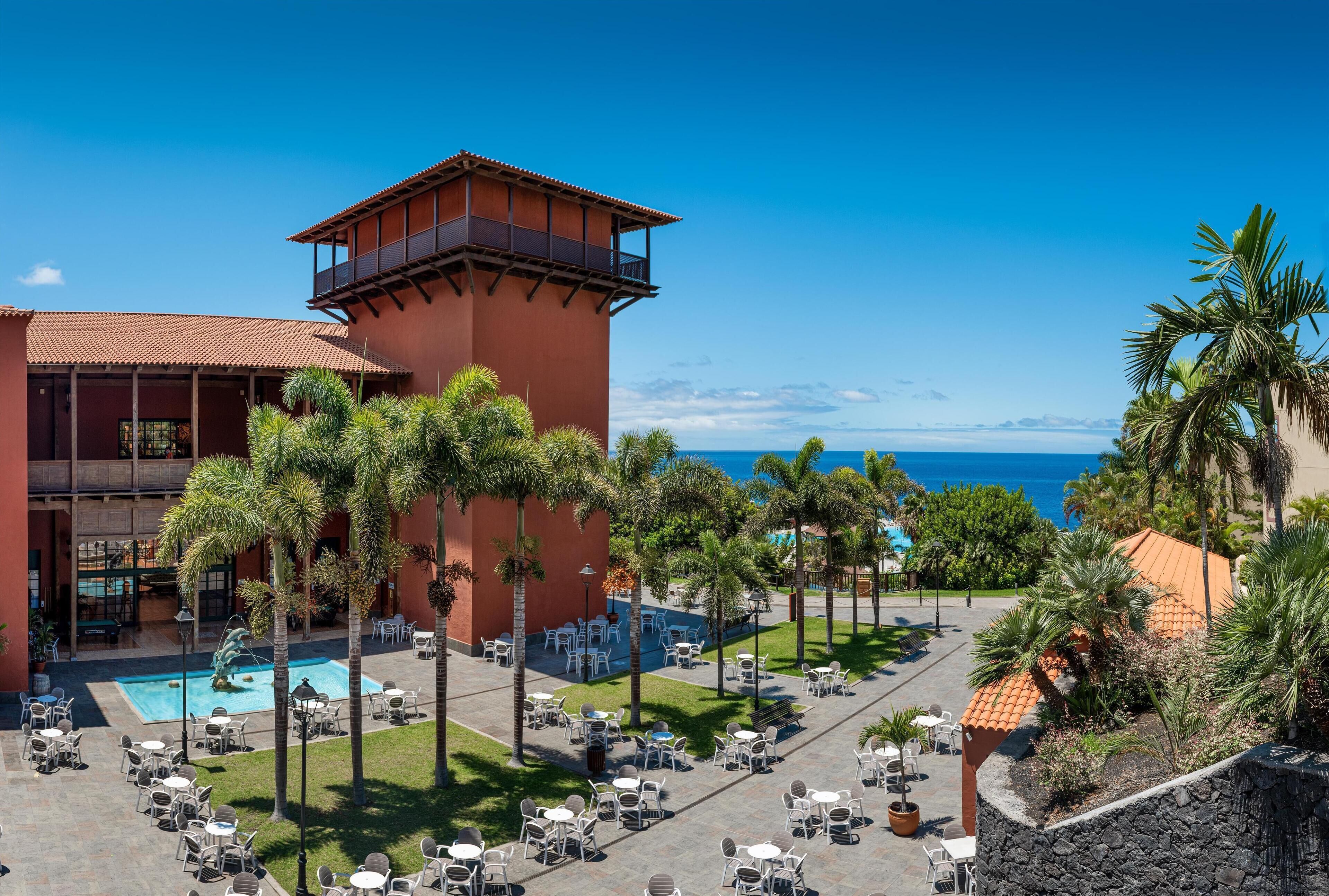 A resort with a pool, outdoor seating, and a view of the ocean.