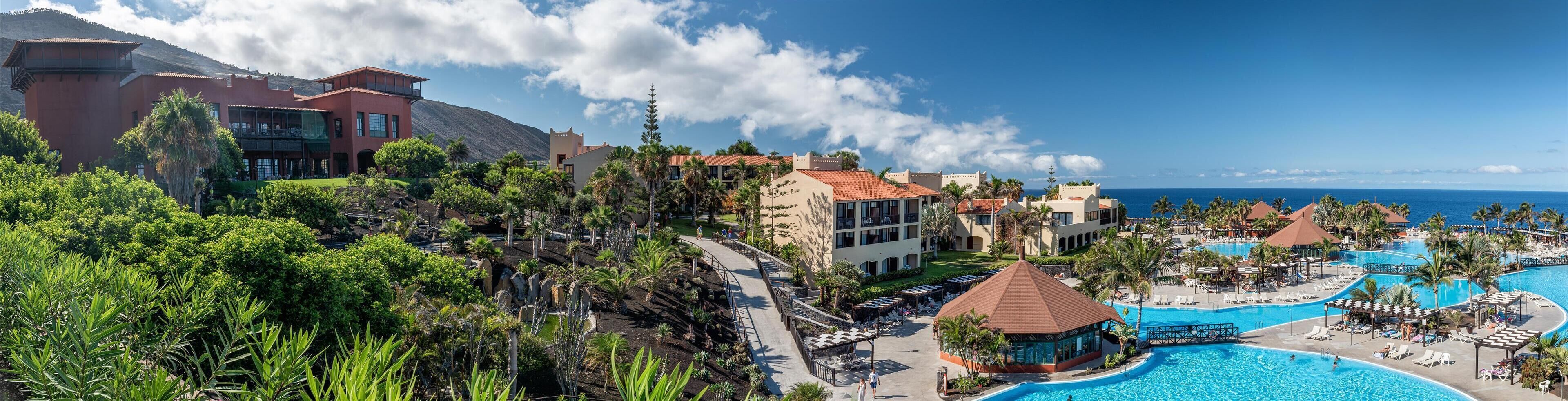 Ein Resort mit großem Pool, mehreren Gebäuden und einem Bergpanorama.